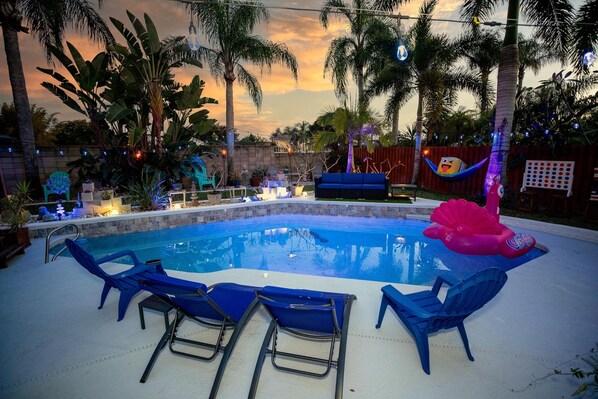 A swimming pool with blue lounge chairs, surrounded by palm trees and decorative lights. - Gorgeous Urban Oasis W/hot Tub, Heated Pool And Private Movie Theater 3 Bedroom Home by RedAwning (Melbourne)