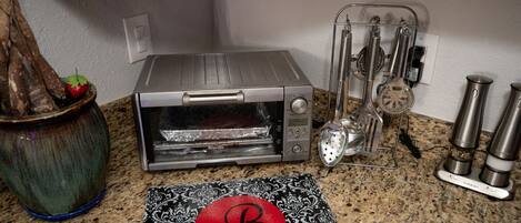 A kitchen with a toaster oven, a spice rack, and a decorative mat with a letter 'B'.
