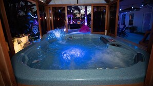 Un bain à remous doté d’une cascade, entouré de poutres en bois et de portes en verre.