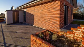 Un edificio moderno de ladrillo con techo plano, una antena parabólica y una estructura pequeña adosada.