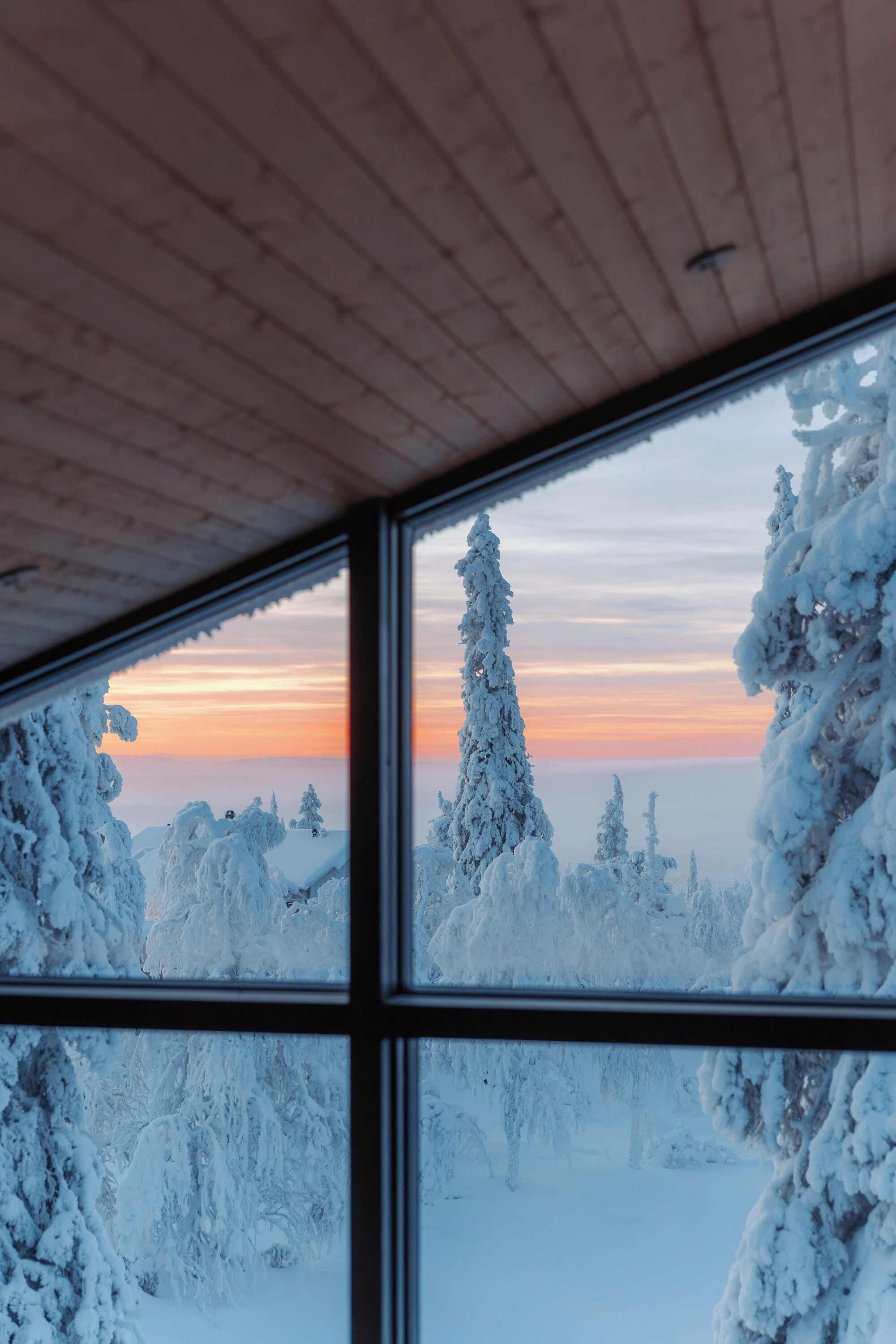 Une pièce dotée d’une grande fenêtre donnant sur un paysage enneigé au coucher du soleil.