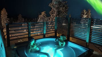 Un bain à remous offrant une vue sur le ciel nocturne et les aurores boréales.