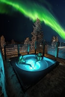 A hot tub with a view of the night sky and the Northern Lights.