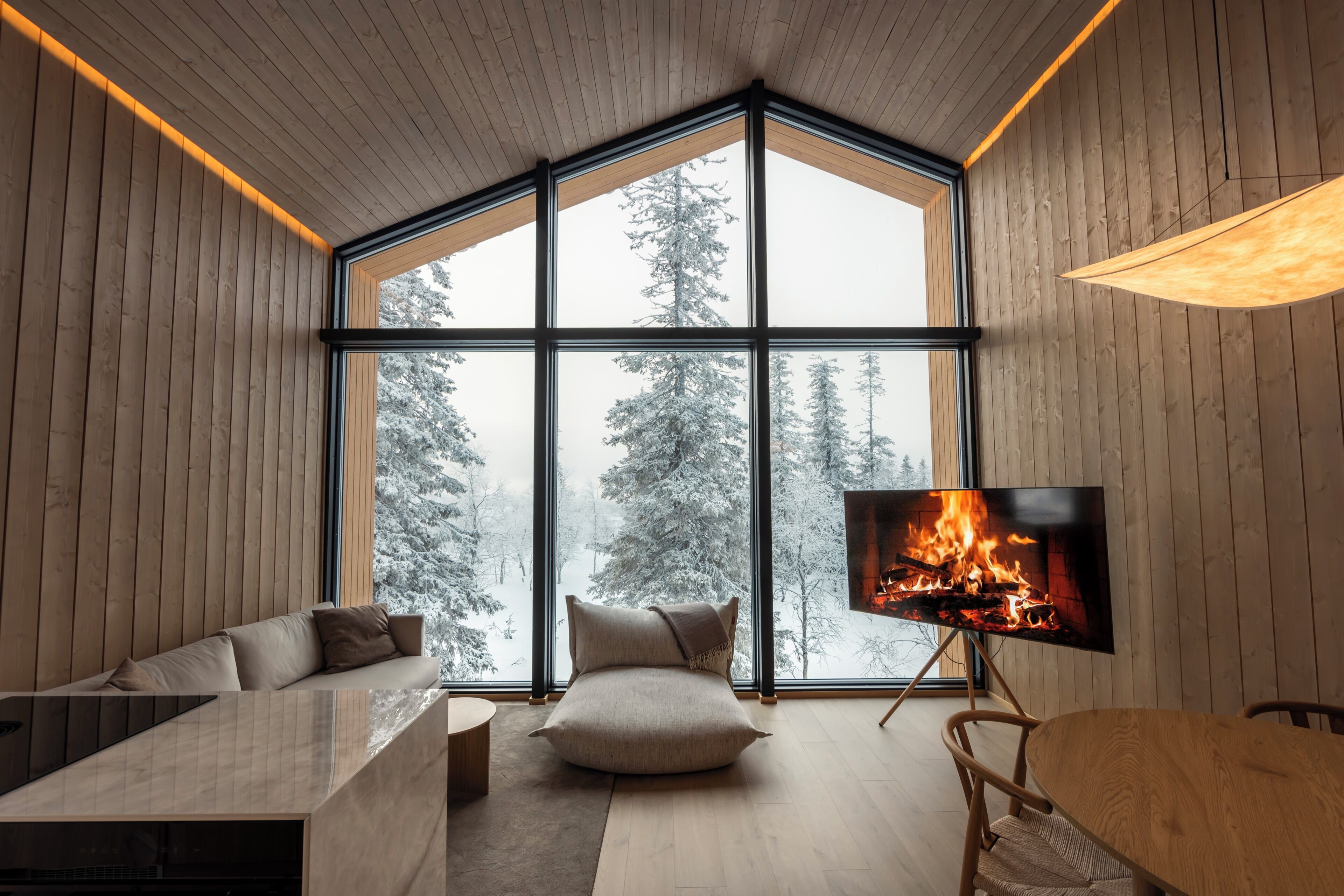 Un intérieur moderne avec une grande fenêtre, une cheminée, un canapé et un coin repas.