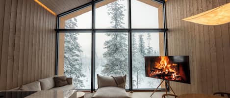 Un intérieur moderne avec une grande fenêtre, une cheminée, un canapé et un coin repas.
