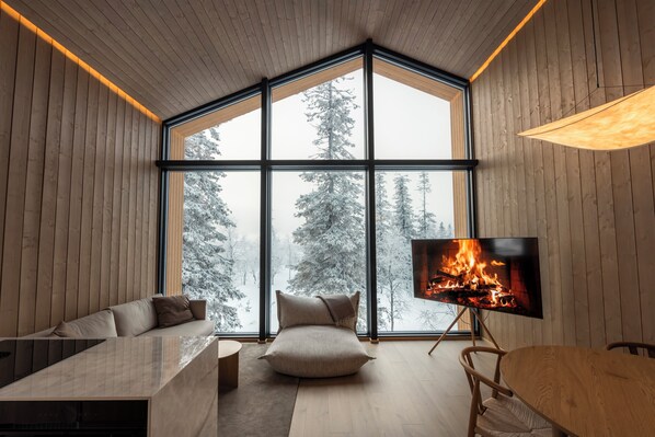 Un interior moderno con un ventanal grande, una chimenea, un sofá y un comedor.
