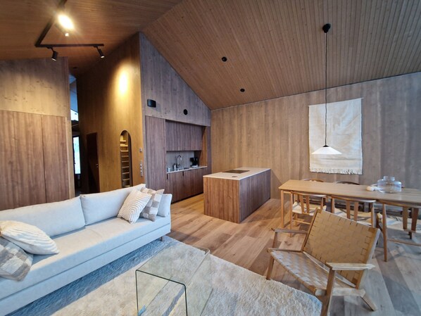 Un interior moderno con sofá, mesa de comedor, sillas y zona de cocina.