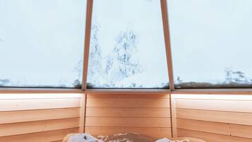 Une chambre avec un lit, des oreillers et une fenêtre donnant sur un paysage enneigé.