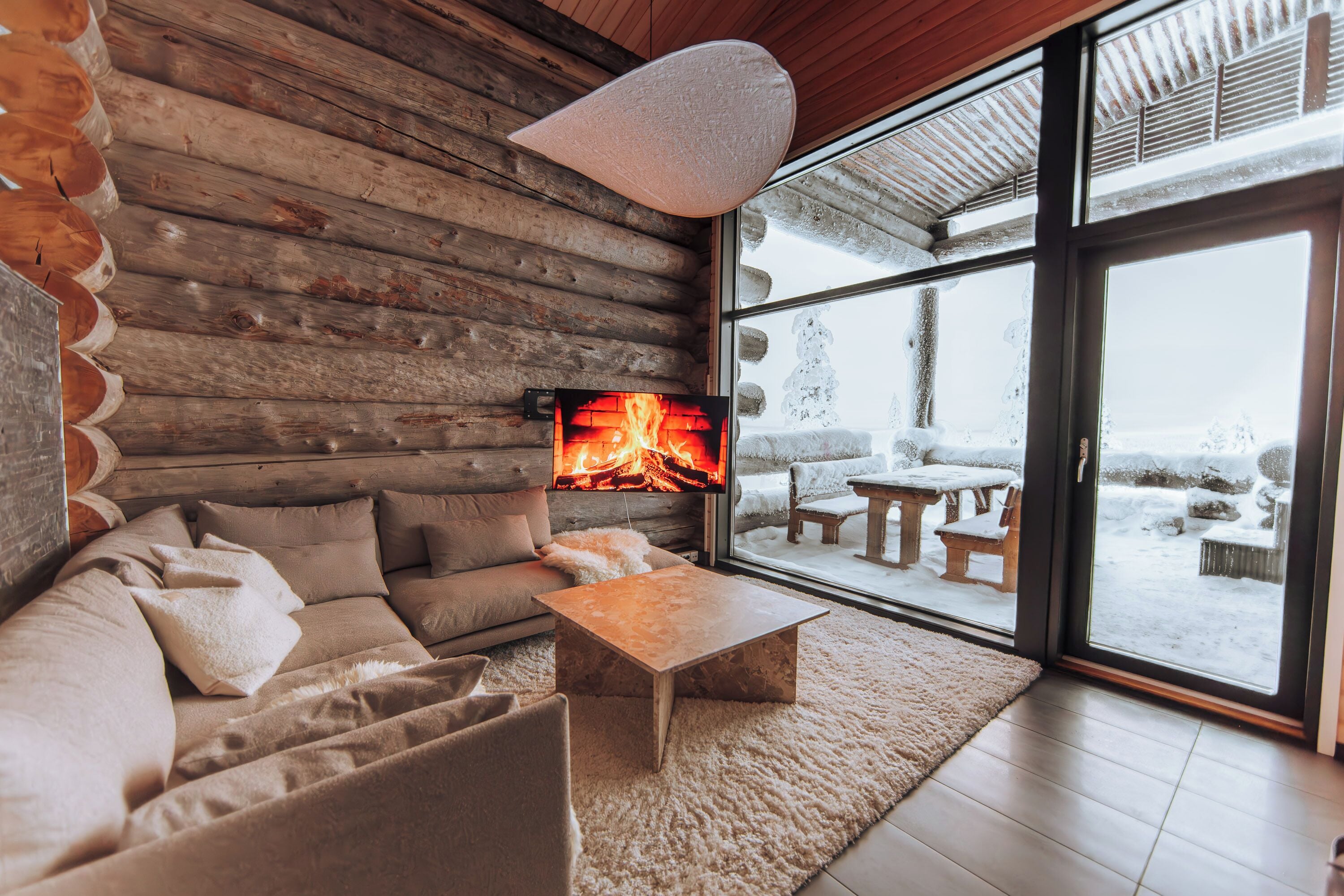 Interior de una cabaña de troncos con sofá, mesa de centro y chimenea.
