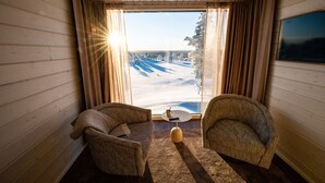 A cozy room with two armchairs, a small table, and a large window offering a view of a snowy landscape. - Aurora Collection Saariselkä (Saariselka)