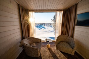 A cozy room with two armchairs, a small table, and a large window offering a view of a snowy landscape.