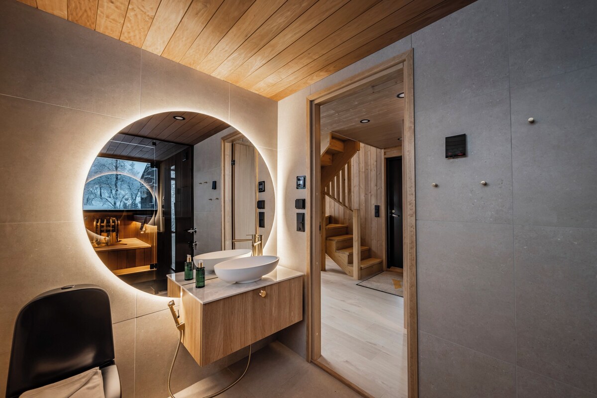 Une salle de bain moderne avec un grand miroir, un meuble-lavabo en bois et une vue sur un escalier en bois.