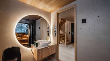 A modern bathroom with a large mirror, wooden vanity, and a view of a wooden staircase.