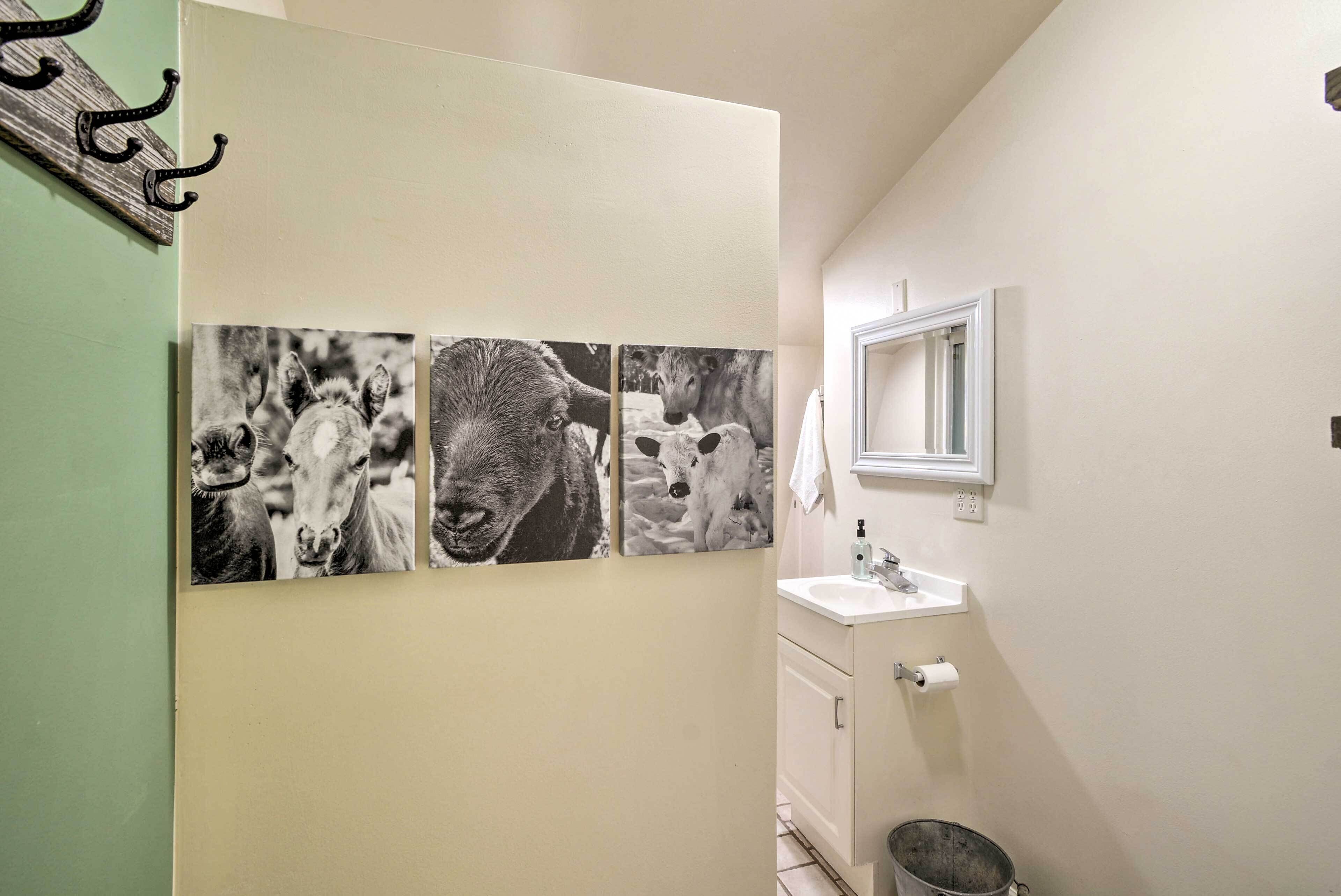 Ein Badezimmer mit Waschbecken, Spiegel und drei schwarz-weißen Kuhfotografien an der Wand.
