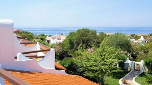 A coastal view with a clear sky, a beach, and lush greenery.