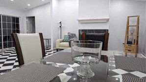 A modern living room with a checkered floor, a glass coffee table, a sofa, and a fireplace. - Villa Camellia 5bed/4.5 bath with private pool and golf course view (Lehigh Acres)