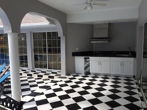 Une cuisine avec un sol à carreaux noirs et blancs, des armoires blanches et un comptoir noir.