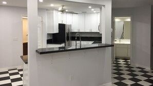 A modern kitchen with a black countertop, white cabinets, and a large mirror. - Villa Camellia 5bed/4.5 bath with private pool and golf course view (Lehigh Acres)