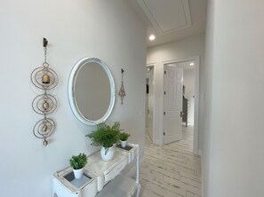 A hallway with a white console table, a large mirror, and decorative wall art.