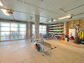 Un espacio interior amplio con ventanas grandes, un banco de metal, bicicletas y una pared de kayaks.