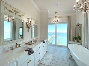 A luxurious bathroom with a large bathtub, multiple sinks, and a view of the ocean.