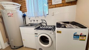 Een wasruimte met een Dox ProFlo boiler, een Betta wasmachine en een wasbak.