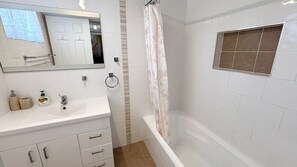A bathroom with a white sink, mirror, and shower curtain.