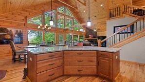 Een ruime keuken met houten keukenkastjes, een groot eiland en een stenen openhaard.