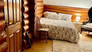 A cozy log cabin-style bedroom with a bed, chair, and a nightstand with a lamp. - Stunning 4-bed Chalet in Bran With Superb Panorama (Bran)