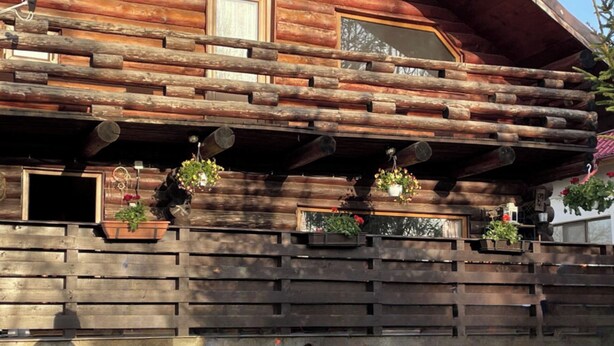 A rustic log cabin with a balcony, potted plants, and a table with various items. - Stunning 4-bed Chalet in Bran With Superb Panorama (Bran)