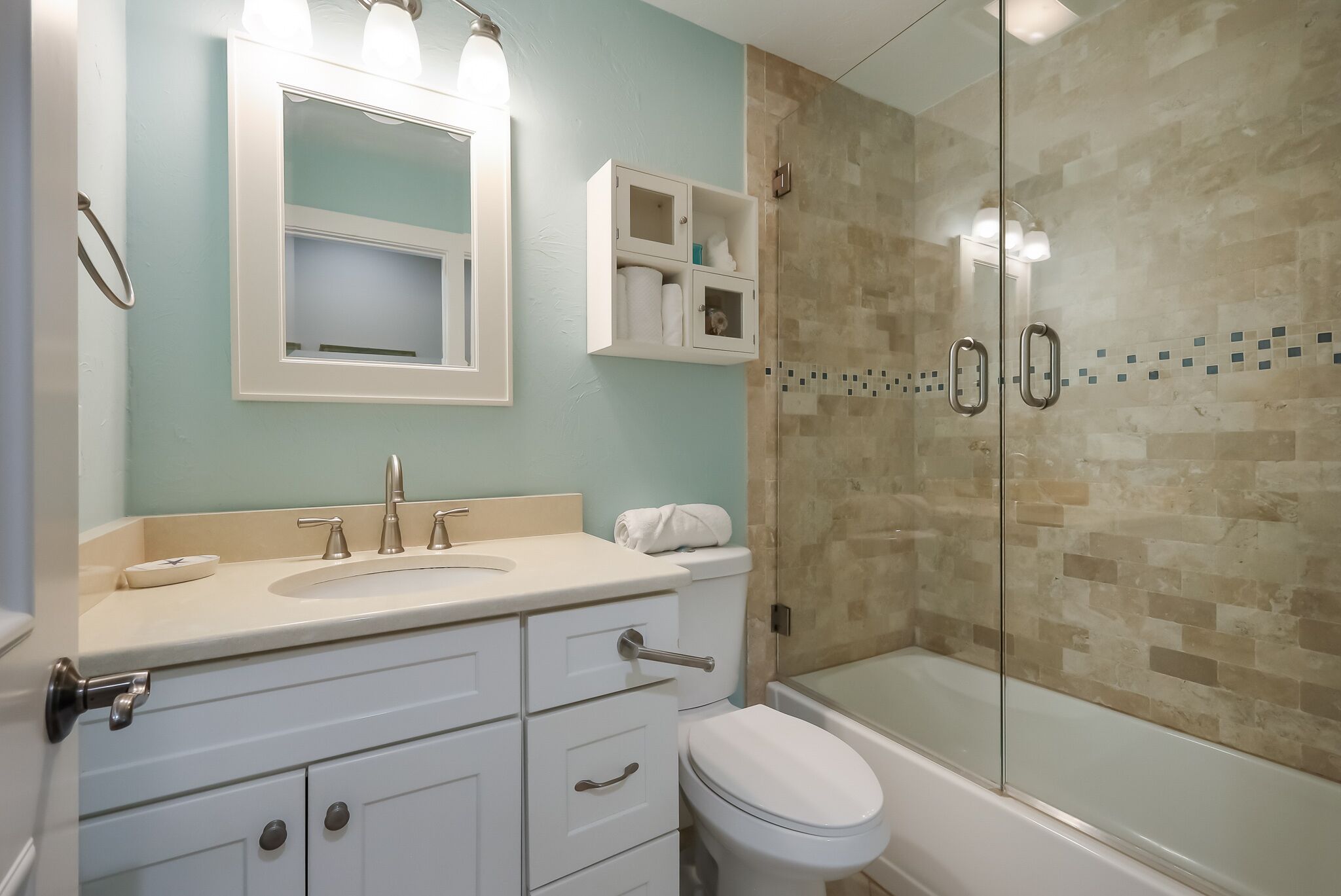 Un baño moderno con cabina de ducha de vidrio, un lavabo blanco y un inodoro.