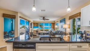 A modern kitchen with a central island, stainless steel appliances, and a view of the ocean.