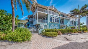 A two-story house with a balcony, a gated entrance, and a paved driveway.