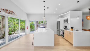 A modern kitchen with a central island, white cabinetry, and stainless steel appliances.