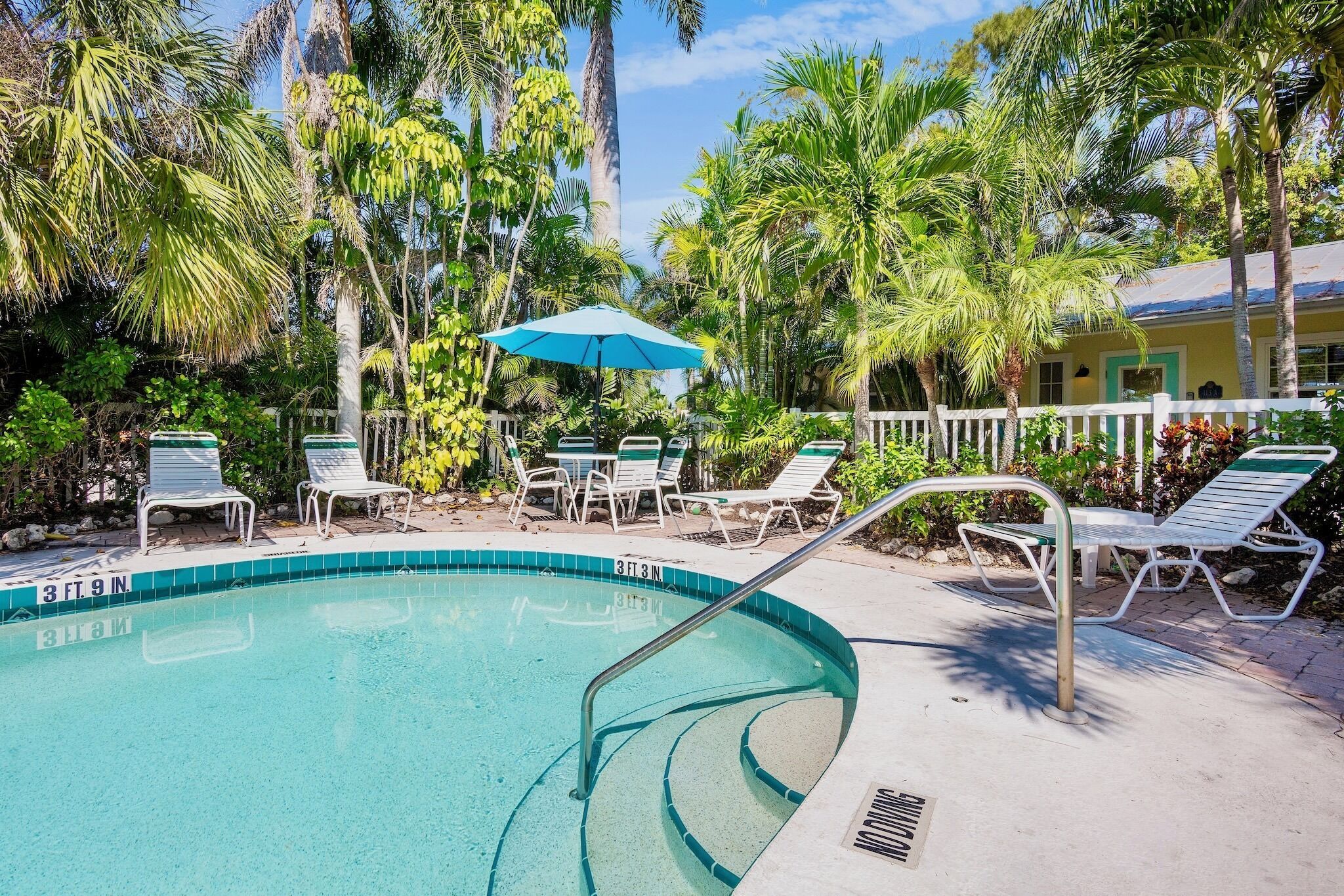 A pool area with lounge chairs and a blue umbrella.
