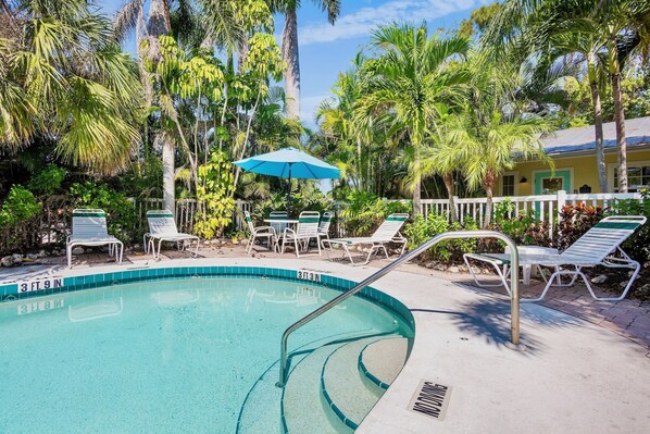 Un espace piscine avec des chaises longues et un parasol bleu.