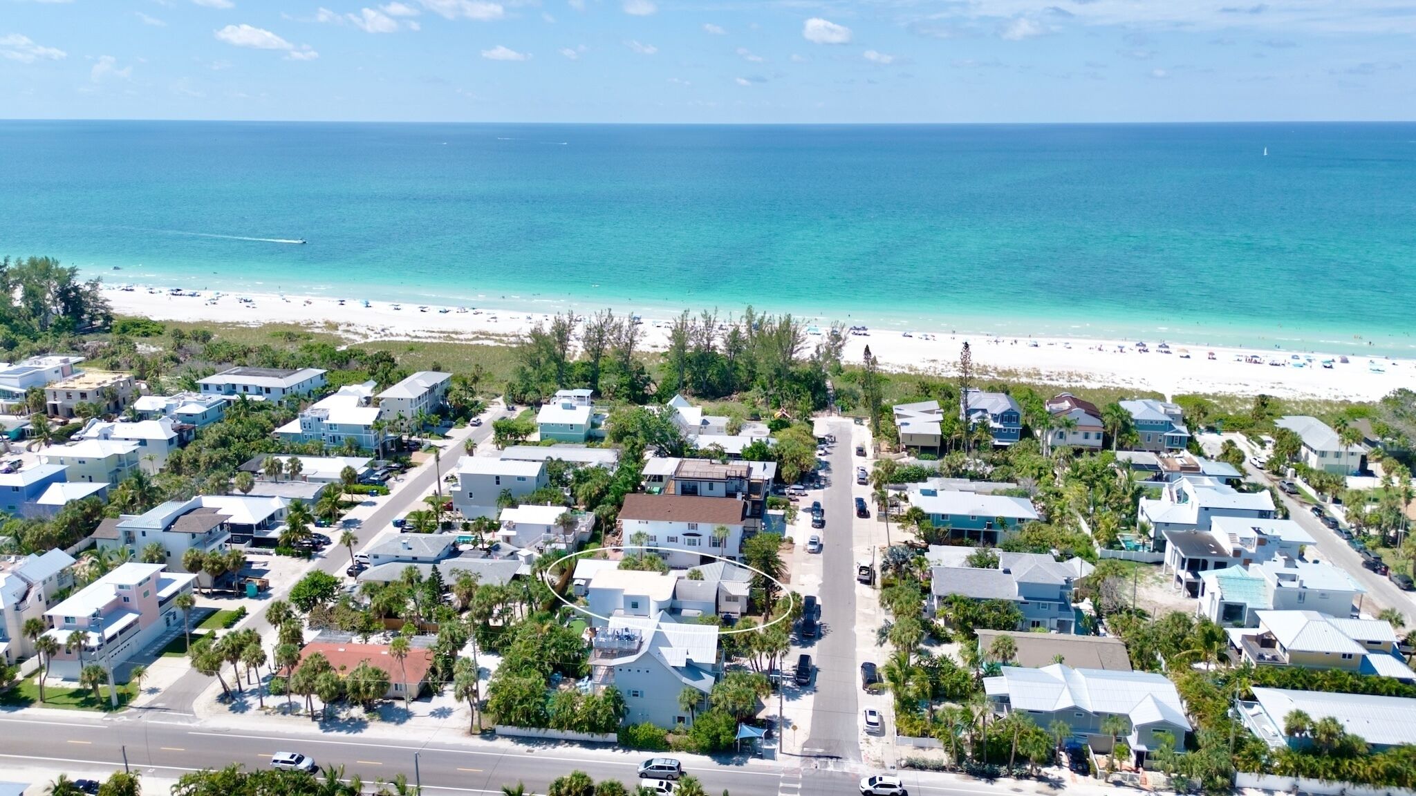 A coastal residential area with houses, a beach, and a clear view of the ocean.