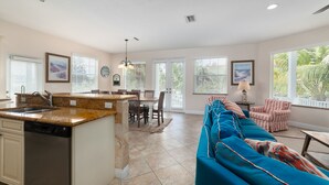 A spacious kitchen with a dining area, a living room with a sofa, and a dining table.