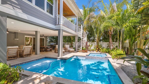 A modern house with a pool, outdoor furniture, and tropical plants.