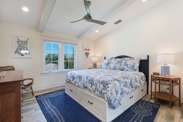 A bedroom with a bed, a ceiling fan, a window, and a nightstand.
