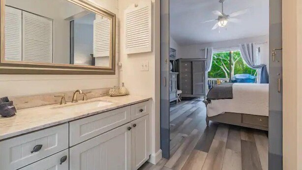 A bathroom with a large mirror, vanity, and a ceiling fan. - Hammock Dreams - Canal Home with Pool and Dock Near Beach (Anna Maria)