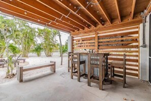 Relax in a serene outdoor space surrounded by lush tropical plants and palm trees, with comfortable seating and dining areas.