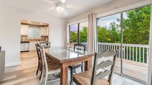 A dining area with a glass table and chairs, a ceiling fan, and a view of the outdoors. - Hammock Dreams - Canal Home with Pool and Dock Near Beach (Anna Maria)