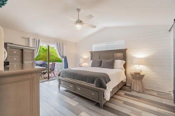 A bedroom with a bed, bedside table, and a ceiling fan.
