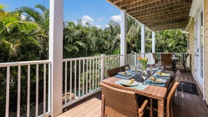 A covered outdoor dining area with wicker furniture and a view of lush greenery. - Poseidons Palace! Family Fun and Gulf Views! (Holmes Beach)