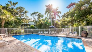 A swimming pool with a white fence, lounge chairs, and a covered area. - Beach Home with Pool Access and Private Patio with BBQ Grill! - Little Dream (Holmes Beach)