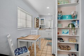 Une cuisine de taille réduite avec des meubles blancs, une table en bois et une chaise blanche.