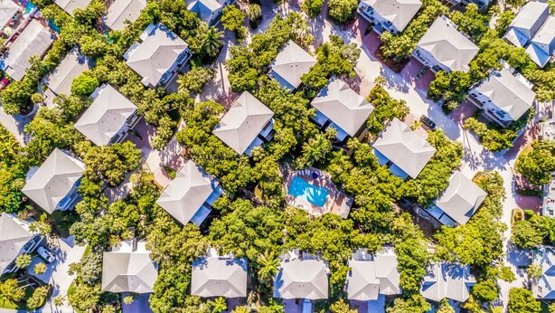 An aerial view of a residential area with uniformly shaped houses, surrounded by lush greenery and a central swimming pool. - Beach Home with Pool Access and Private Patio with BBQ Grill! - Little Dream (Holmes Beach)
