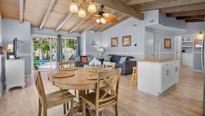 A spacious living area with a wooden dining table, a sofa, and a kitchen island.
