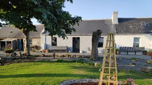 A garden with a wooden ladder, a stone building, and a tree. - Bespoke 1 Bed Cottage in Dunbeath Village (Dunbeath)